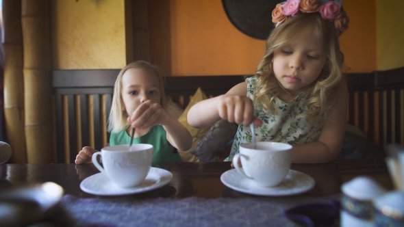 Two Cute Little Girls Are Having Tea In a Cafe