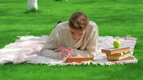 Young Smiling Man Lying With Tablet On Lawn