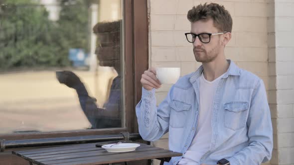 Relaxing Man Drinking Coffee while Sitting Outdoor in Cafe