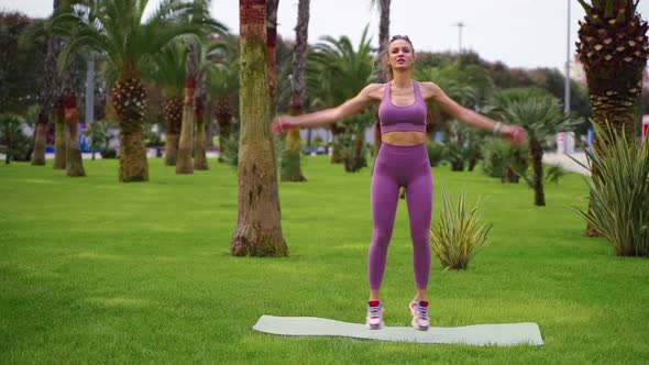 Aerobic Training at Park at Summer Day Young Woman is Jumping Lifting Hands Up