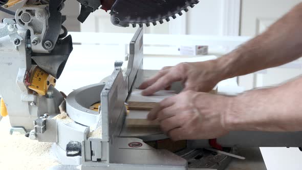 Worker Cuts Wood Baseboard on the Power Miter Saw