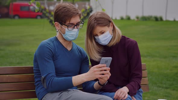 Two cute people look closely on phone and find out from news, coronavirus pandemic is over.