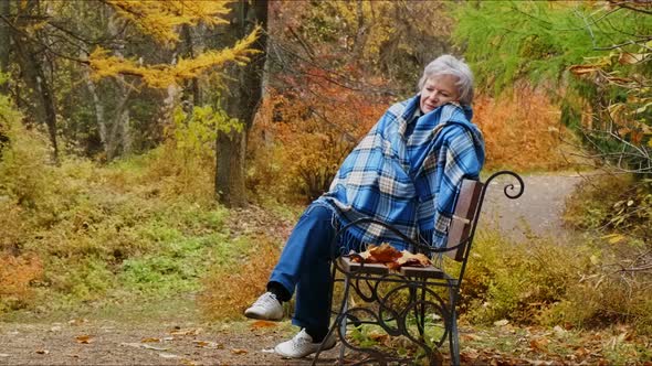 Elderly Woman Walks in the Park in Autumn and Relaxes.