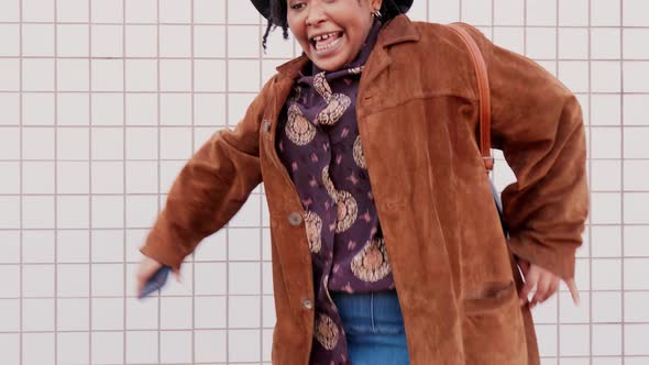 Black woman dancing in the street with smartphone in hand