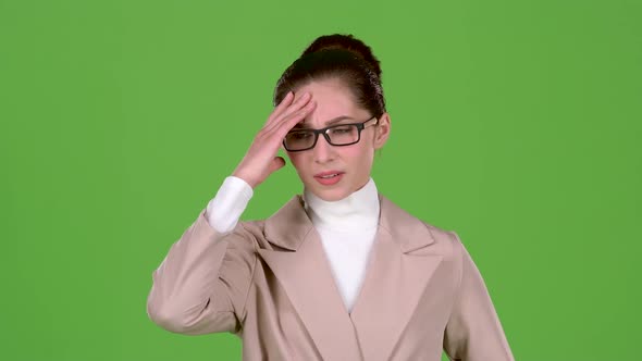Girl in a Business Suit Is Standing in the Studio, She Has Terrible Headaches. Green Screen. Slow