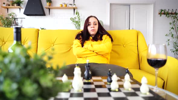 Young Upset Woman Playing Chess Sitting on Sofa