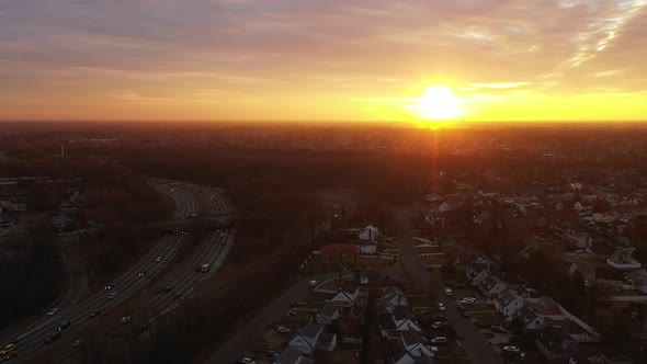 A drone view of a Long Island neighborhood at sunrise with a cloudy but blue sky. The camera dolly i