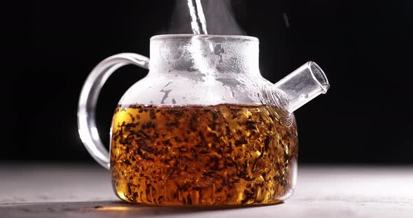 Process of Brewing Black Tea in Glass Transparent Teapot at Dark Background