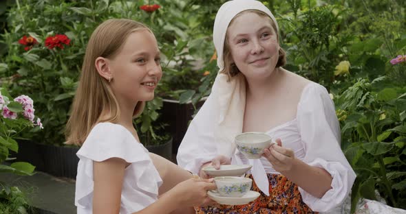 Cute Happy Girls Drinking Tea in Summer Garden