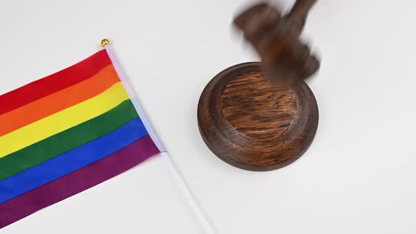 The Judge Beats the Gavel Next to a Handheld Lgbt Flag on a White Table