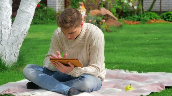 Guy Sitting In The Garden And Using Digital Tablet