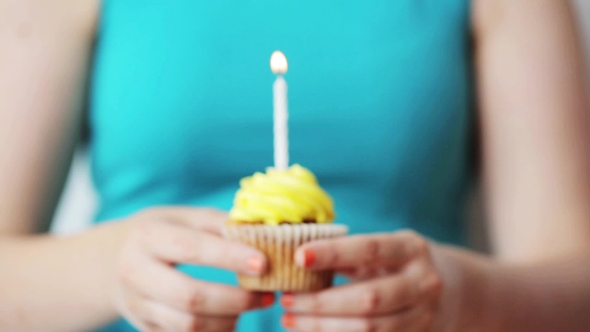 Woman With Burning Candle On Birthday Cupcake