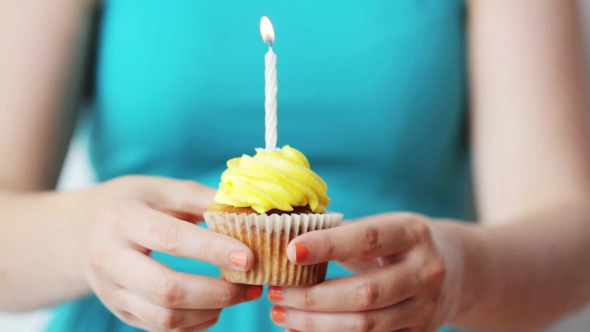 Woman With Burning Candle On Birthday Cupcake