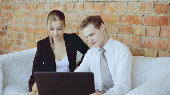 Businesswoman And Businessman Discussing Business With Laptop On The Sofa