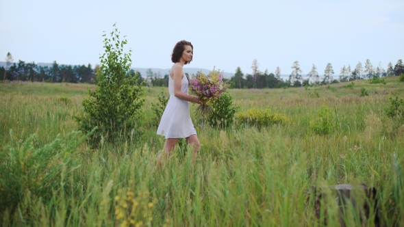 Beautiful Inspired Woman Talking On a Blossoming Field With a Bouquet Of Wildflowers.