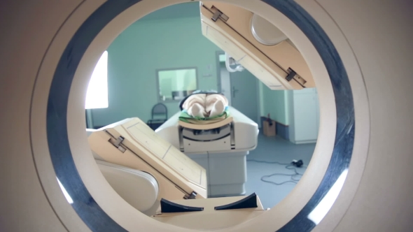 Unrecognizable Hospital Patient Lying On MRI, Tomograph, Scanner, Moving To And From The Camera