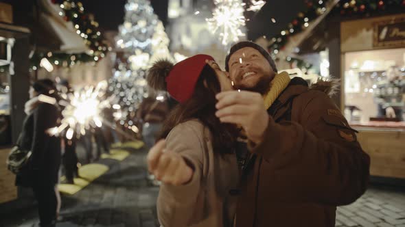 Romantic Couple in Love Hugging and Burning the Sparklers at Festive Street Fair