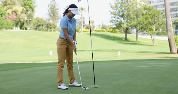 Woman Golfer About To Sink Her Putt