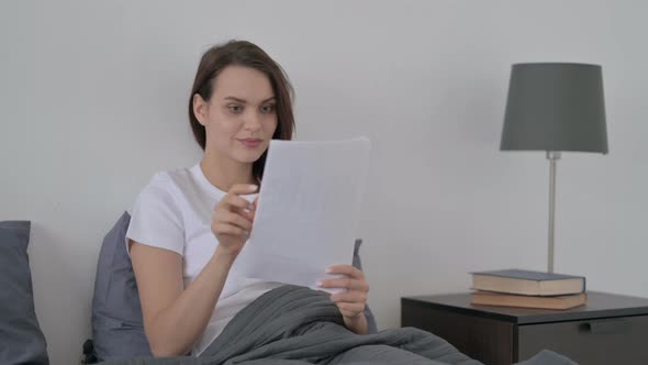 Woman Reading Documents While Sitting in Bed