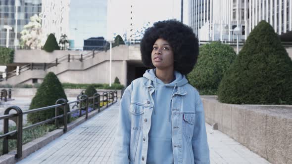 Thoughtful Young African Woman with Afro Hairstyle Walking in City Street