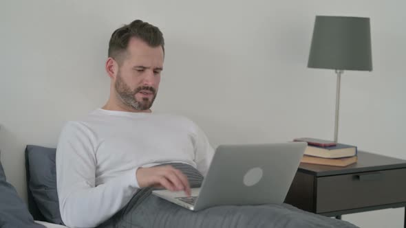 Man with Laptop Having Headache in Bed