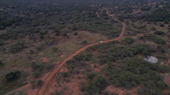4x4 suv white vehicle driving a dirty road in African game reserve farm. Aerial