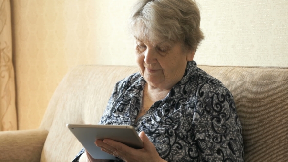 Old Woman Holding a Digital Tablet And View Photos