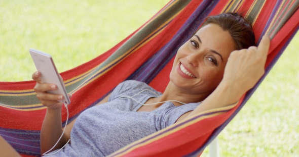 Happy Young Woman Listening To Music In a Hammock
