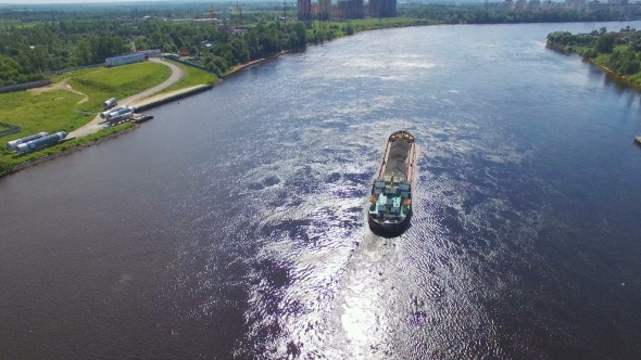 aerial view of cargo barges filled with gravel, it floats on the river on the background of the city
