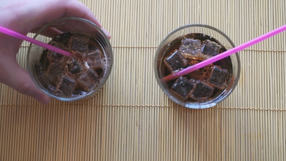 Two Hands Put Two Glasses Of Cola With Ice
