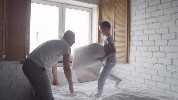 Happy Father and Son Play Fighting with Pillows