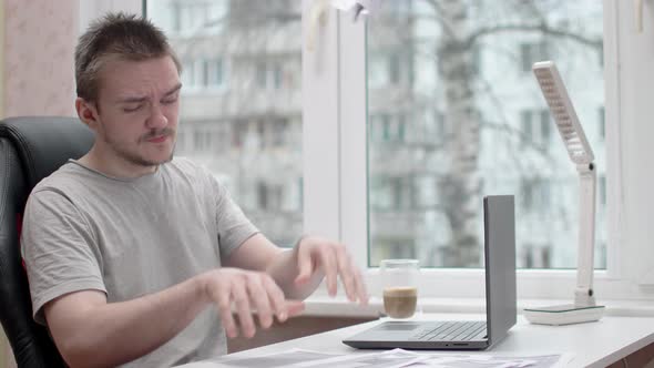 A young guy is reading documents, he is wearing a gray t-shirt