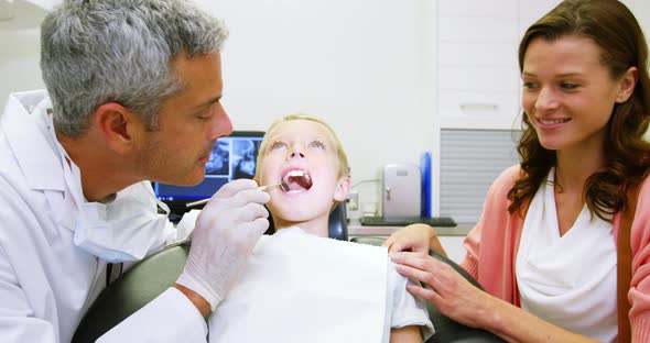 Dentist examining young patient with dental tool