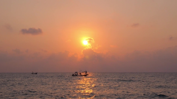 Silhouette Of Asian Fishing Boat Sailing At Sunset In Sea