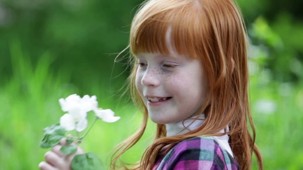 Little Red-haired Girl Sniffing Blossoming Branch