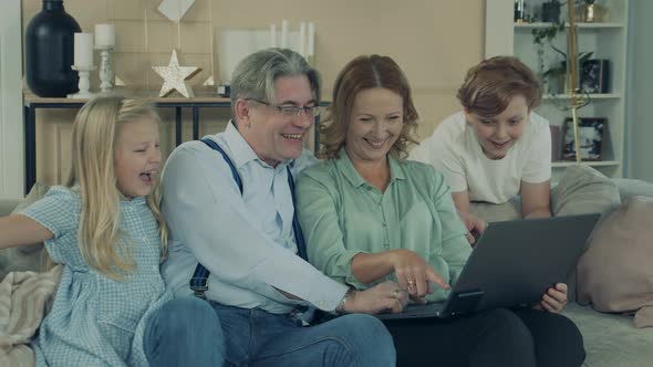 Grandparents and Grandkids Are Using a Laptop and Laughing