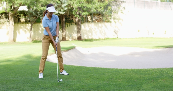 Woman Golfer About To Play a Stroke On The Green