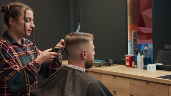 Barbershop: a woman barber cuts a client's man's hair