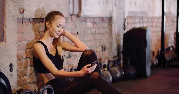 Fit Young Woman Using Smartphone In Gym