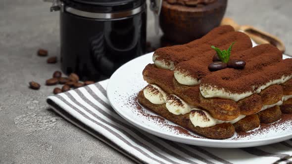 Classic Tiramisu Dessert and Coffee Grinder on Ceramic Plate on Concrete Background