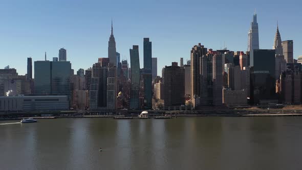an aerial view over a calm East River on a sunny day with blue skies. The drone camera dolly in and