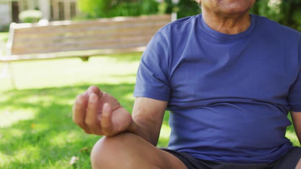 Video of relaxed biracial senior man practicing yoga in garden
