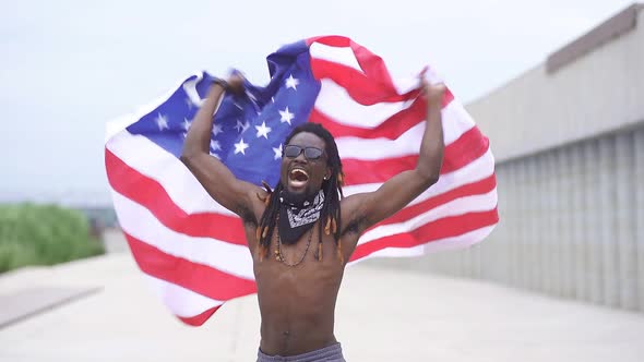 Dark-skinned Male Protester Waves an American Flag in the Street