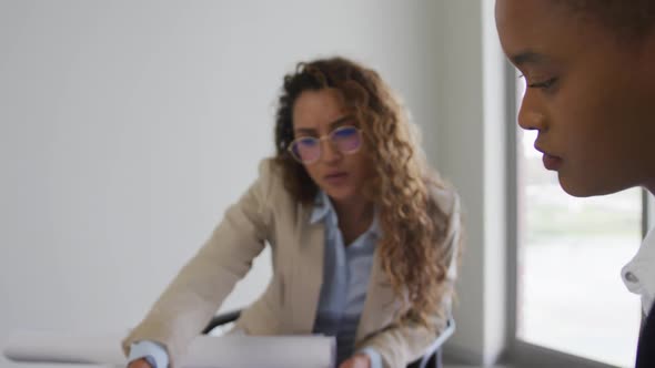 Biracial female architects talking and checking architects plans in modern office