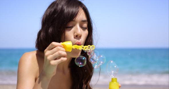 Young Woman Blowing Soapy Iridescent Bubbles