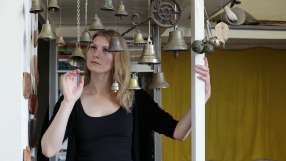 Young Beautiful Woman Touching Bells and Looking Sad at Camera