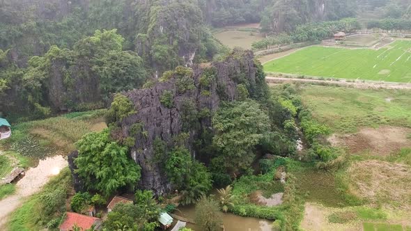 Aerial ascend over giant limestone rock in Vietnamese countryside of Tam Coc, Ninh Binh, Vietnam