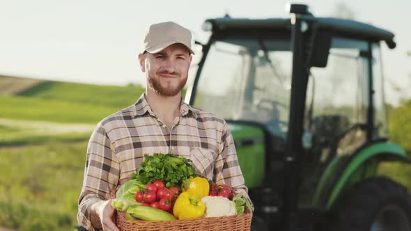 A Farmer is Standing Near a Field and Holding a Basket of Vegetables From the Field
