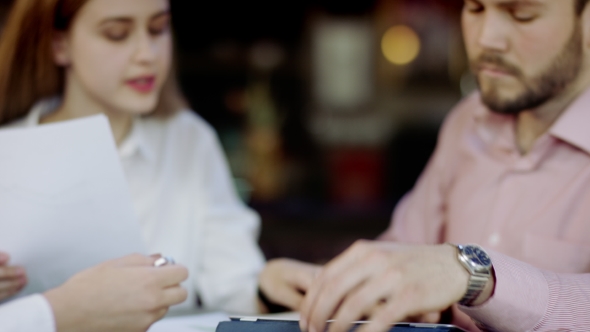 Half Length Of Young Business Men And Women Sitting In a Bar Discussing Something