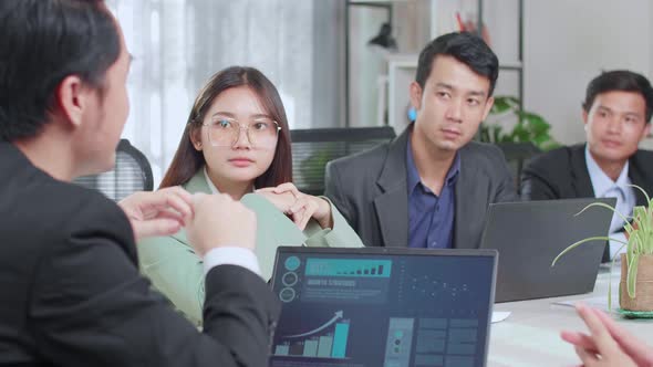 Asian Executive Explains Company's Vision And Potential To His Employees. Statistics Show On Laptop